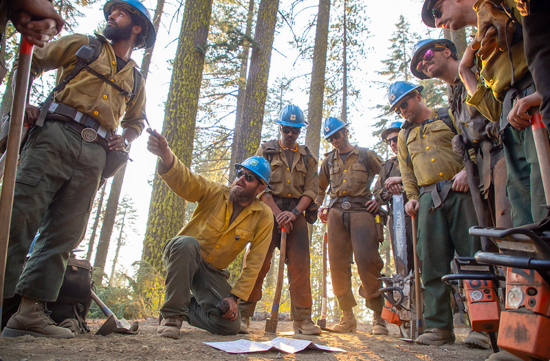 Photo of firefighters gathered in a circle for a field briefing at Shasta Lake Fire